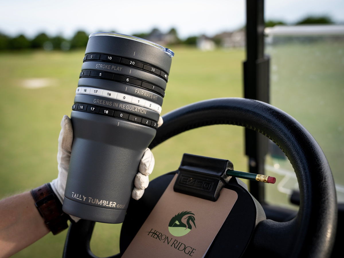 Person holding a tumbler with a golf cart and green field in the background