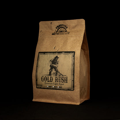 A package of Frontier Coffee Company's Gold Rush light roast coffee, featuring a graphic of a prospector on a brown paper bag style packaging.