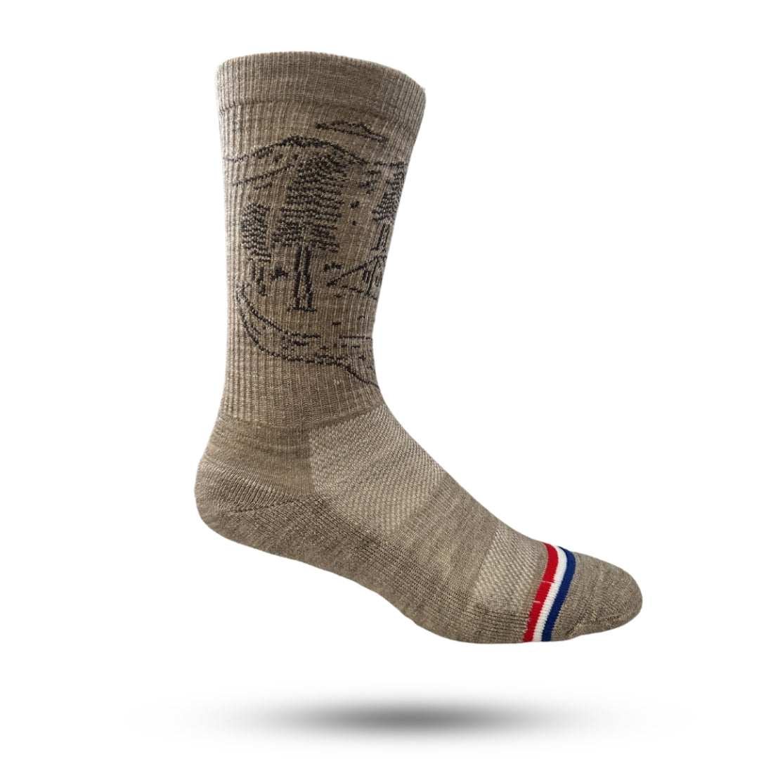 A pair of light brown adventure socks with a cushioned sole and a reinforced heel and toe seam, featuring a striped design with red, white, and blue.