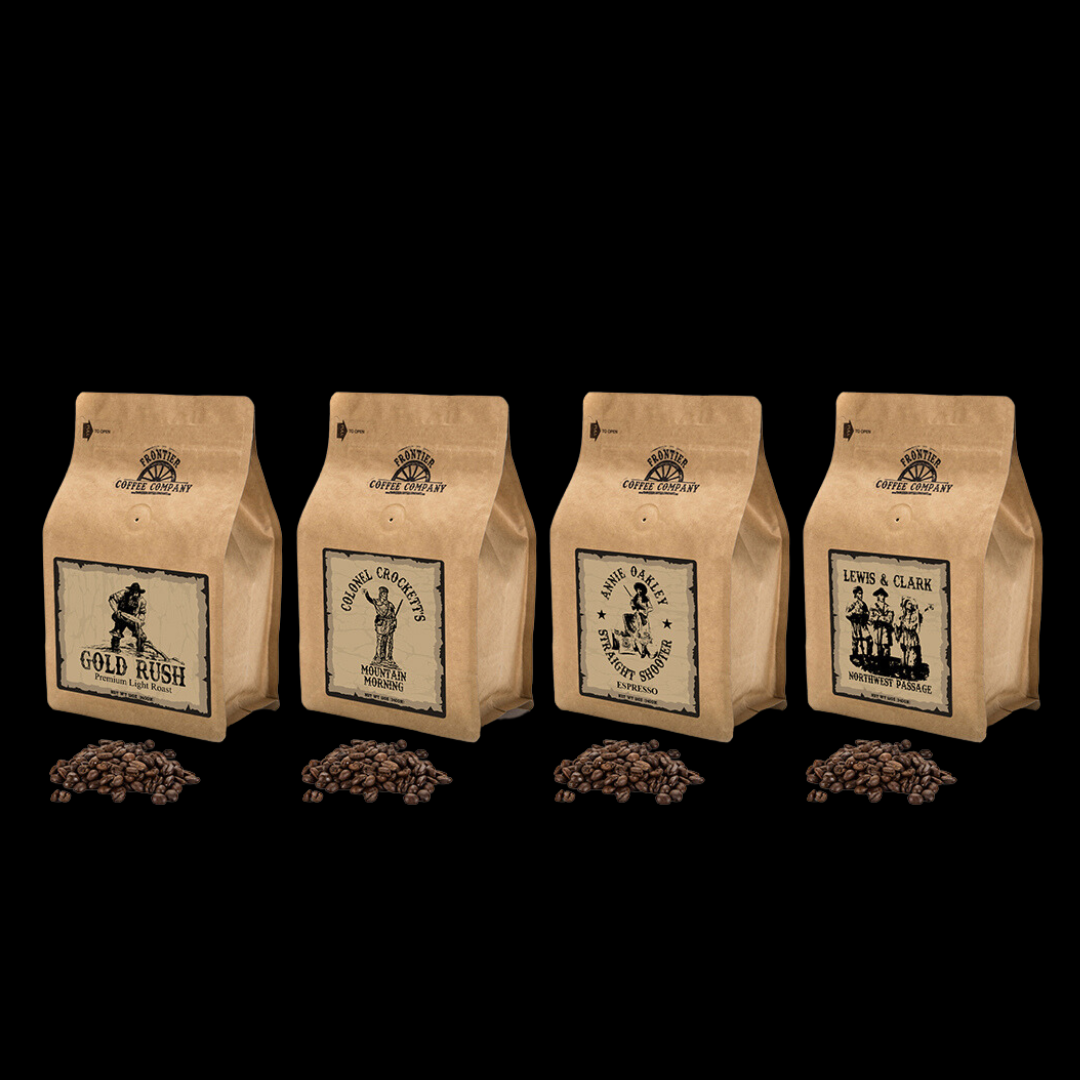 Four bags of Frontier Coffee with different roast levels indicated by the labels, ranging from light to dark, displayed in a row with coffee beans scattered in front of each bag.