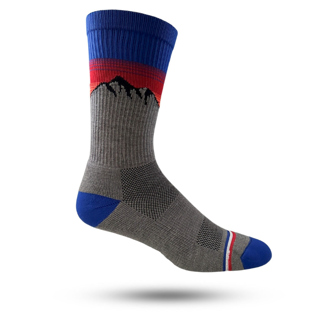A pair of lightweight merino wool socks with a cushioned sole and antimicrobial mesh panels, featuring a geometric pattern with blue and red mountains.
