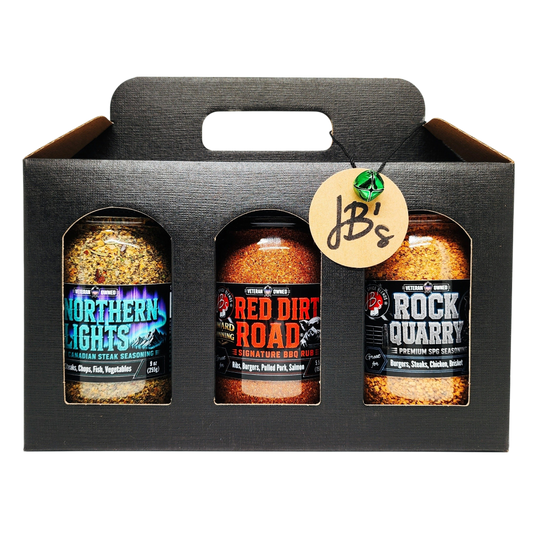 A three-pack of JB's smoked meats seasoning bottles in a black cardboard carrier. The bottles are labeled Northern Lights, Red Dirt Road, and Rock Quarry, and are shown against a clean white background.