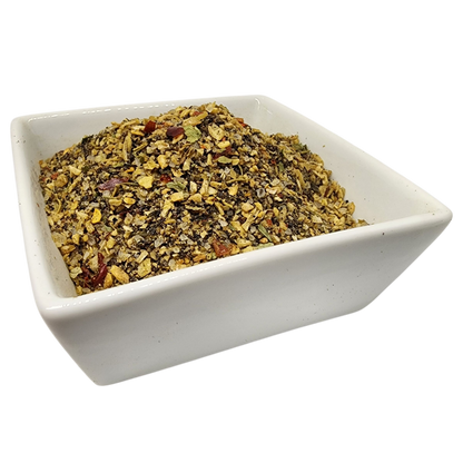 A white square ceramic bowl filled with a textured mixture of dried herbs, seeds, and small red pieces, isolated on a white background.