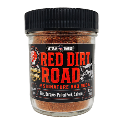 A jar of Red Dirt Road Signature BBQ Rub by Spice Bites, featuring a black ribbed lid and a black label with bold red and white text, set against a plain white background.