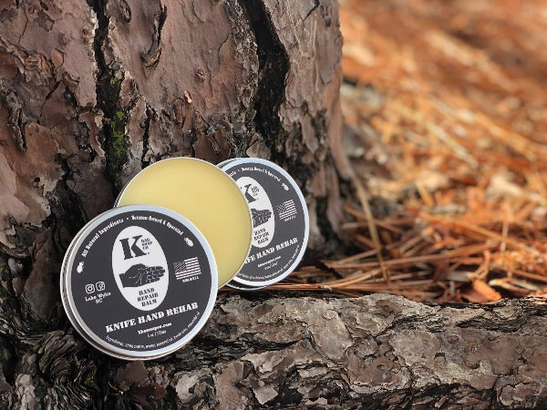 
                  
                    Hand Repair Balm tin open leaning against a tree
                  
                