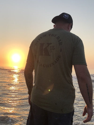 Man with OD Green Triblend K Bar logo shirt at sunset